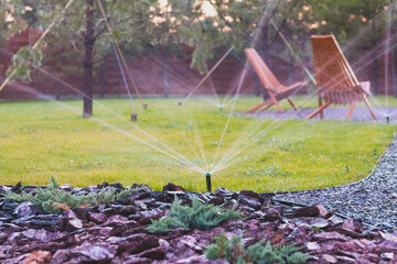 Automatic lawn watering system. Sprinkler, Water spashes on green grass.