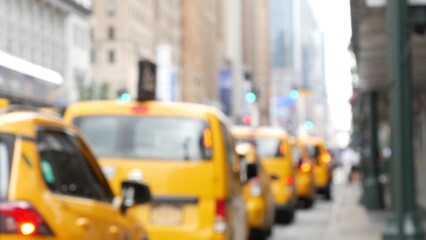 New York City. Row of yellow taxi cars on Manhattan street. Many taxi cabs on Midtown 8th avenue. Medallion taxicab in line near Penn Station waiting for passengers. Defocused urban scene, pedestrians