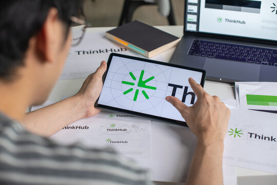 Male Asian graphic designer working in an office studio, using tablet, designing logos and showcasing the corporate identity and logo design process.