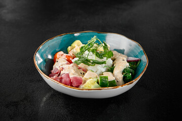 Fresh Tuna Poke Bowl with Vegetables and Herbs in Cerulean Bowl on Dark Surface