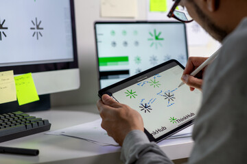 Close-up shot of a graphic designer making notes on logo designs, using a tablet, designing logos, and showcasing the corporate identity and logo design process.