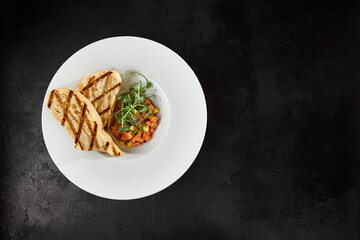 Delicious Salmon Tartare with Avocado and Grilled Ciabatta on Dark Background Top View