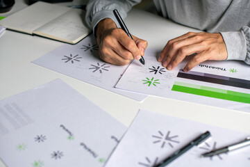 Close-up shot of a graphic designer making notes on logo designs and showcasing the corporate identity and logo design process.