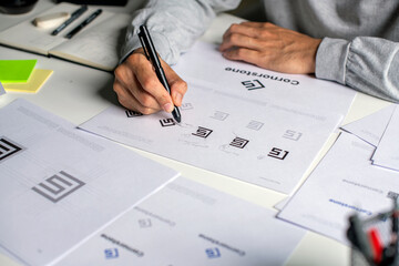 Close-up shot of a graphic designer making notes on logo designs and showcasing the corporate...