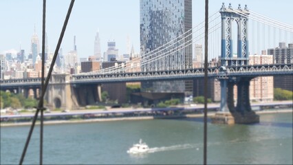 New York City Manhattan Bridge from Brooklyn Bridge view. Empire State building in Midtown. Travel USA, tourist landmark. NYC skyline cityscape. Iconic architecture thru cables over East River water.