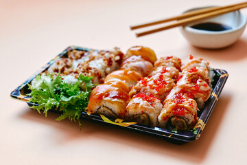 Set of sushi and maki with soy sauce over salmon pastel color background. Take-away food concept