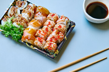 Set of sushi and maki with soy sauce over blue background. Take-away food concept