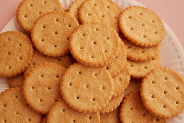 Close-up of saltine crackers on a plate on a pink background, close-up of cookies, freshly baked cookies