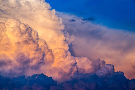Large Cumulonimbus calvus clouds lit by setting summer sun.