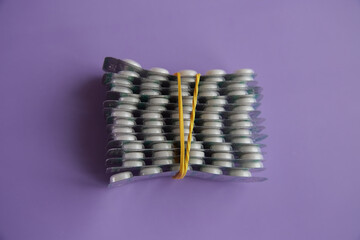 White pills on lilac background, prescription drugs, buying medicines in advance, large dosage of...