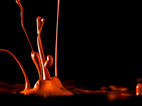 Colorful paint jumping in different forms in front of black background.