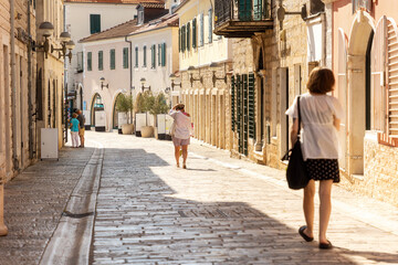 Half-empty cobbled street of old town, illuminated by the midday sun. Summer heat of Mediterranean climate and siesta