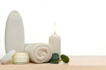White candle, white towel, white cleaner. Glass container for cream.