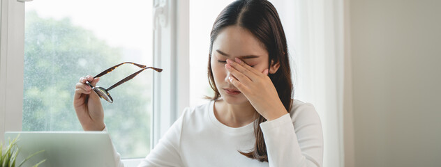 Eye problem concept, fatigue asian young woman tired eyes, irritated rubbing eye dry relief vision pain after work on laptop computer, eye strain, hand holding glasses, suffer migraine, bad blurry