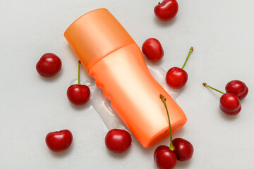 Body and face cream in a plastic container. Lying on spilled cream. Red cherry.