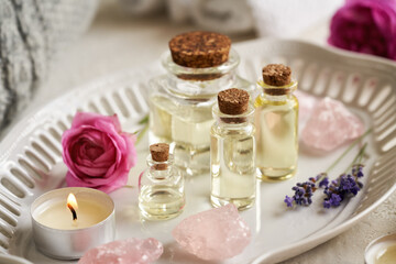 Bottles of aromatherapy essential oil with lavender and rose de Mai flowers and rose quartz stones. Spa treatment.