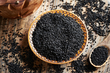 Black cumin or Nigella sativa seeds in a wooden bowl. Healthy nutritional supplement.