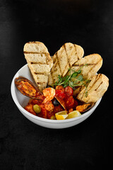 Delicious Seafood Saute in Tomato Sauce with Ciabatta Bread on a Black Background