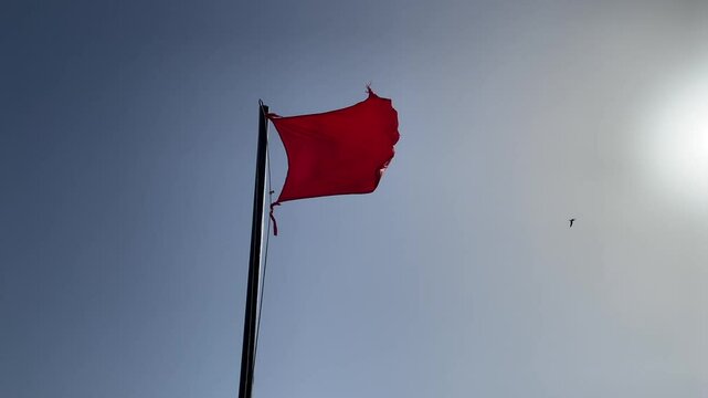 Beach red flag weather wind on blue sky background, The sea has a strong current and big waves. Swimming is prohibited.