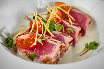 Fresh Tuna Tataki with Garnished Greens and Cherry Tomatoes on White Plate