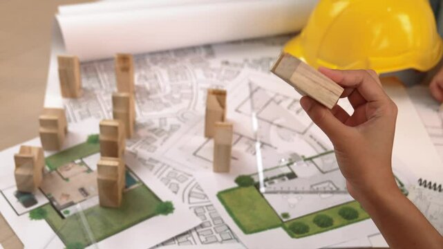 Architect and engineer consider or discuss about building construction using blueprint on table with architectural document, measurement tool and wooden block scatter around at office. Delineation.
