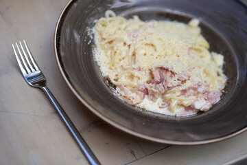 Spaghetti Carbonara with bacon. Carbonara pasta in a ceramic plate on a gray countertop. Traditional Italian cuisine. Top view, close-up with copy space. High quality photo