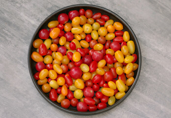 Small red and yellow  tomatoes in a large bowl