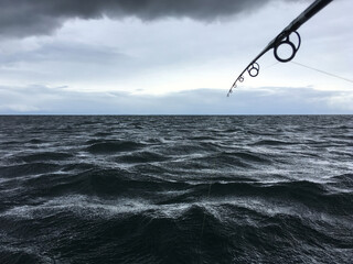 Fishing in stormy sea. Fishing rod in rough weather at the ocean.