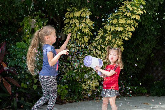 two kids playing with a bubble gun. Bubble machine best toy for small kids. Summer fun activities for kids.