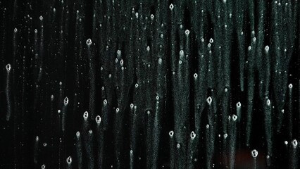 Spray foam water on a black glass screen, isolated background with liquid bubbles flowing over the surface, opposing view scene.