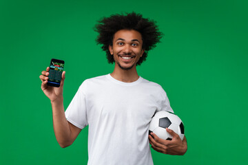 Young happy smiling soccer supporter man showing smartphone with bookmaker's mobile application...