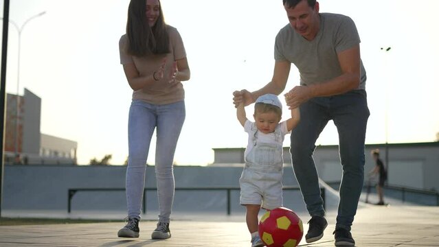 Family day together in park.parents and child relax on family day in park with ball.happy parents with baby together in park. active games on family day.healthy lifestyle in park.happy family concept