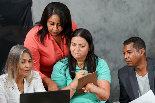 Latina woman with physical disability taking notes during a meeting with her coworkers.