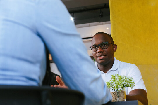 Black male entrepreneur talking during a business meeting in a coffee shop.