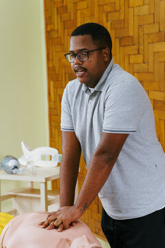 Teacher demonstrating chest compression techniques with a mannequin in first aid training.