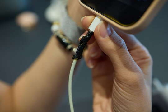 A closeup image showing the process of plugging in a charger into a smartphone wrapped in black tape