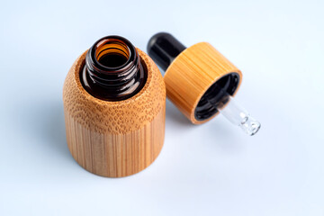 bamboo and glass cosmetic bottle with a dropper on a blue background. Natural cosmetics concept, natural essential oil and skin care products, mockup