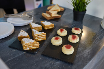 Assorted pastries such as jam tarts and layered desserts beautifully presented on slate trays