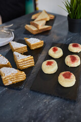 Assorted pastries such as jam tarts and layered desserts beautifully presented on slate trays