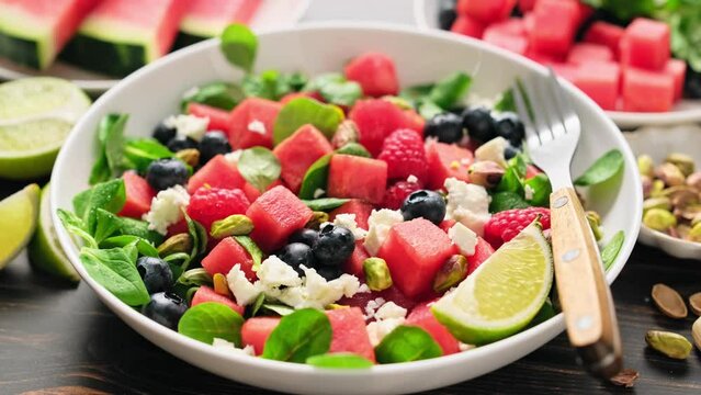 Watermelon and feta cheese salad with blueberry, raspberry, pistachios and fresh greens. Stock video 4k