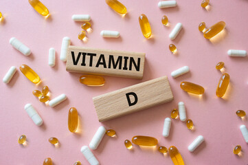 Vitamin D symbol. Concept word Vitamin D on wooden blocks. Beautiful pink background with pills. Medicine and Vitamin D concept. Copy space