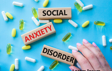 Social Anxiety Disorder symbol. Concept words Social Anxiety Disorder on wooden blocks. Beautiful blue background with pills. Doctor hand. Healthcare and Social Anxiety Disorder concept. Copy space.