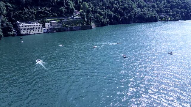 breathtaking tracking shot of aerial view of fast motorboats and slow old boats crossing themselth on water Como lake on a summer morning 3