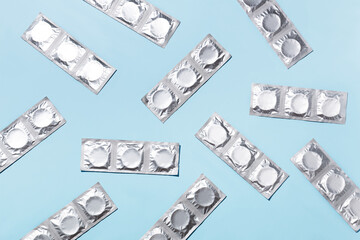 Lots of packages with condoms on a blue background. Top view. 