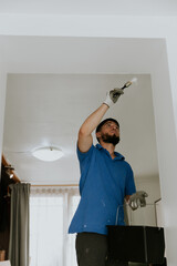 A young man paints the wall with a brush.