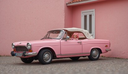 Vintage pink convertible car parked near a pink wall.