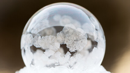 A frozen bubble in the snow. Beautiful frosty patterns on a frozen soap bubble. winter, frosty background. Frozen bubble. soap bubble on snow close up