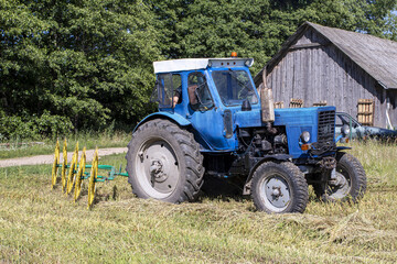 Obraz premium natural lighting. The driver of a blue tractor cleans hay and oats. close-up