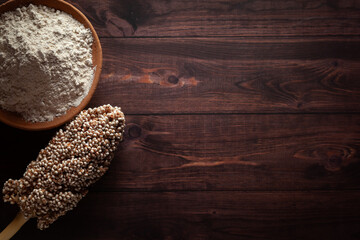 Organic Sorghum Flour (Sorghum bicolor) or Jowar Flour with seeds, isolated on a dark wooden background. Top view.