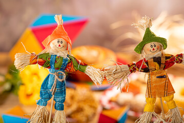 Festa Junina, straw dolls in front and in the blurred background a table full of sweets from the Brazilian Festa Junina, selective focus.